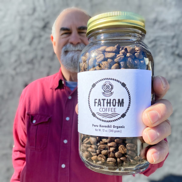 Bob hold a jar of Peruvian coffee roasted by Fathom Coffee